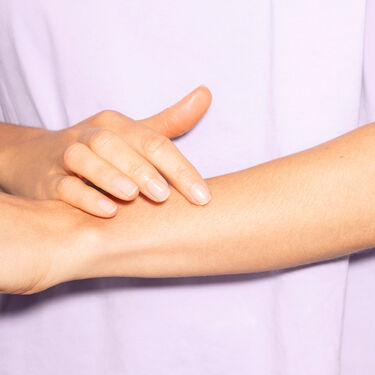 Person trägt QiQu Skin Repair am Arm auf